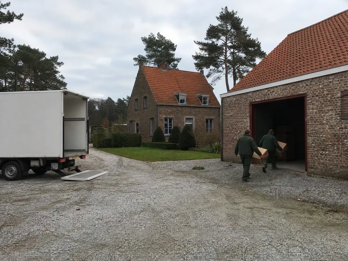 Vrijstaande woning met oude stal in een gehucht van Geel, werkmannen dragen dozen naar een witte vrachtwagen