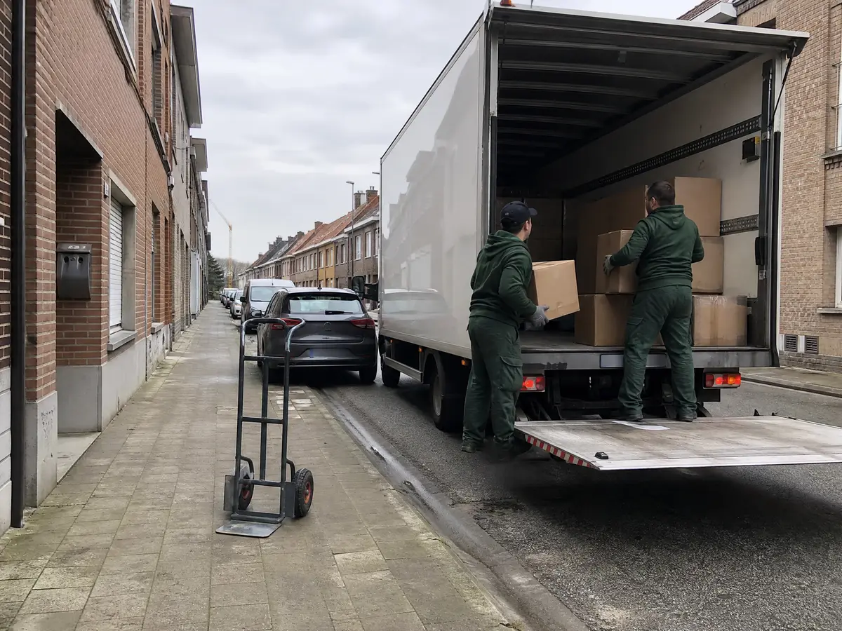Twee medewerkers laden dozen in een witte bestelwagen voor een woning in Willebroek